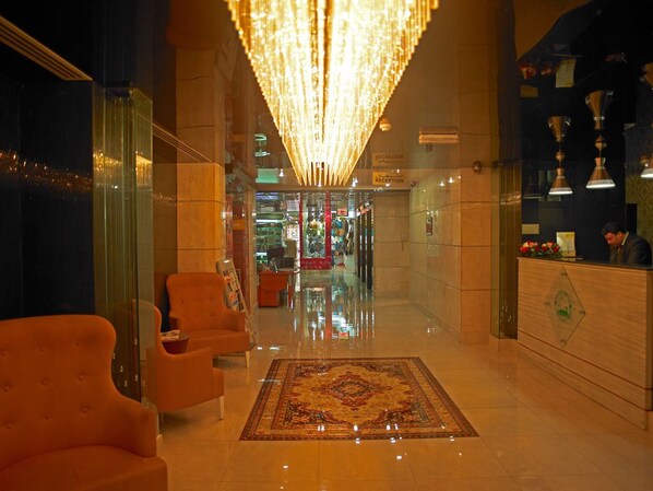 A hotel lobby with a reception desk, seating area, and a chandelier. - Phoenicia Hotel (Dubai)