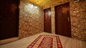 Un pasillo con paredes de piedra, puertas de madera y un tapete estampado.