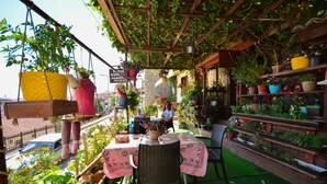 Un patio al aire libre con una mesa y sillas, rodeado de macetas y un jardinero de ladrillo.