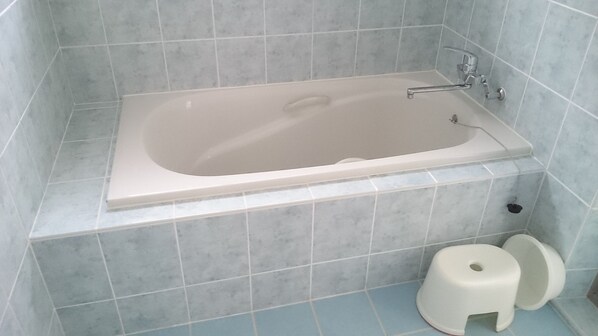 A bathroom with a bathtub, a toilet, and a small stool. - ashipi ginoza (Ginoza)