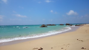 A beach with clear turquoise water, sandy shore, and scattered rocks. - ashipi ginoza (Ginoza)
