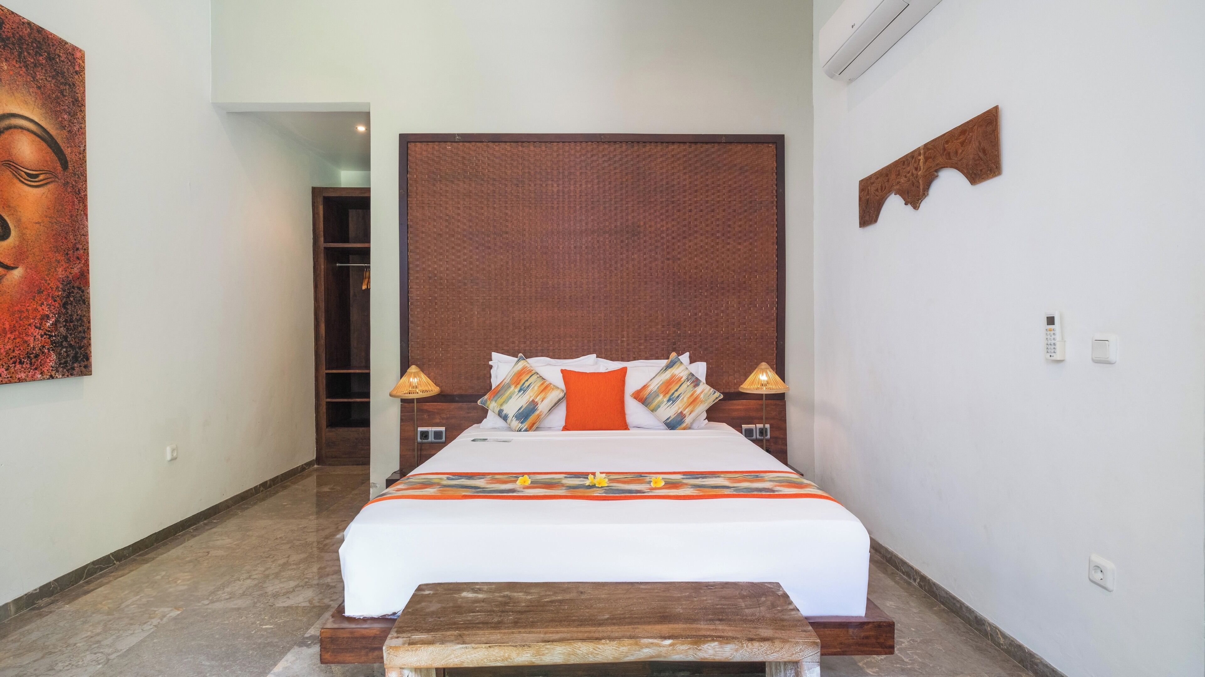 A bedroom with a large bed, a wooden headboard, two bedside lamps, a bedside phone, and a small table.