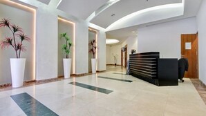 A modern lobby with a reception desk, potted plants, and a curved ceiling design. - Peaceful  Windows of Jerusalem (Jerusalem)