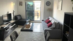 A modern living room with a sofa, a TV, a coffee table, and a dining area. - Peaceful  Windows of Jerusalem (Jerusalem)