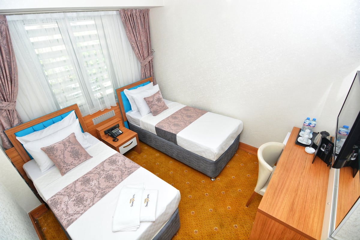 A hotel room with two beds, a desk, a chair, a telephone, and a television.