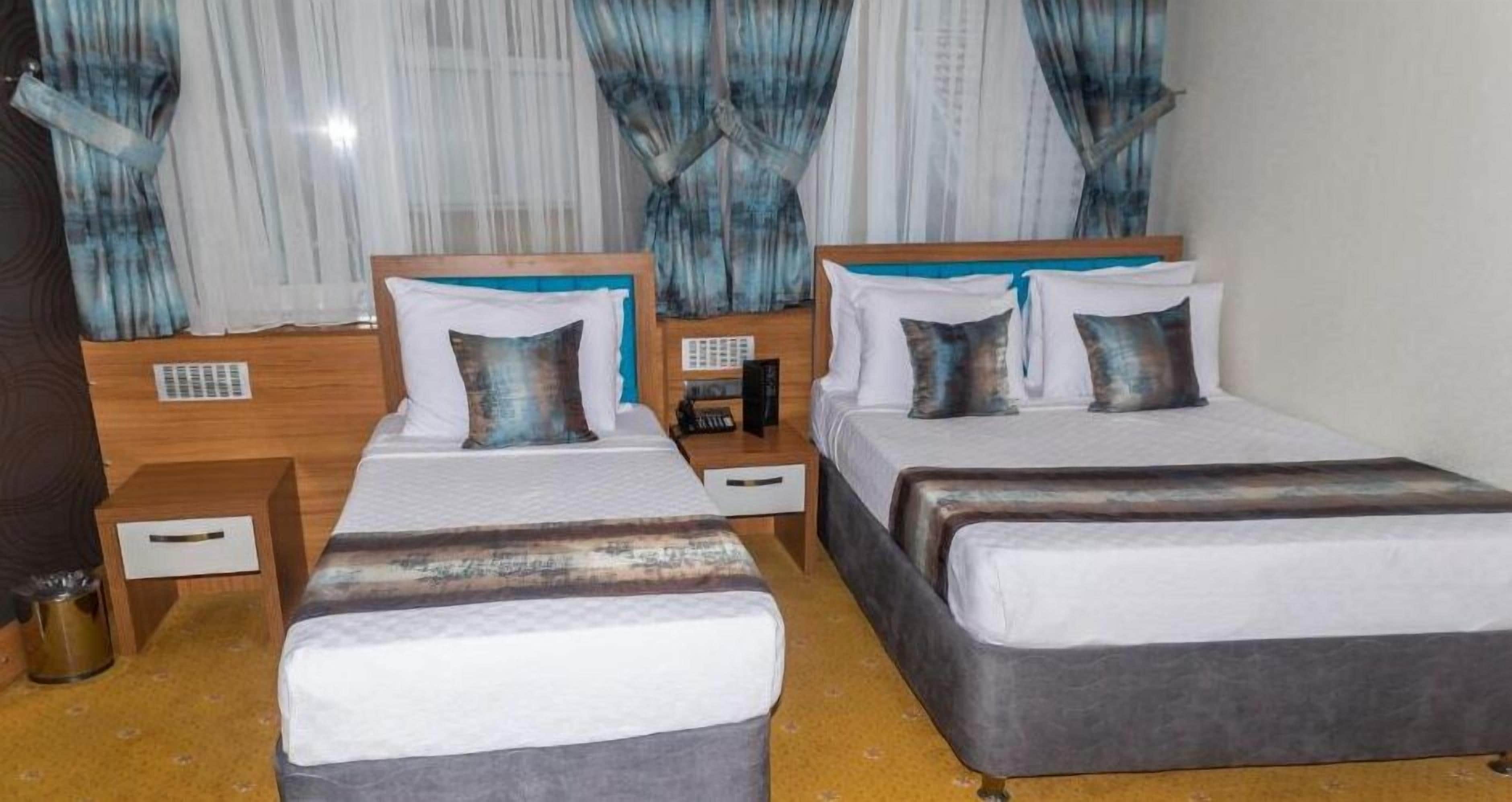 Una camera d'albergo con due letti, una testiera in legno, un comodino e un tavolino da notte.