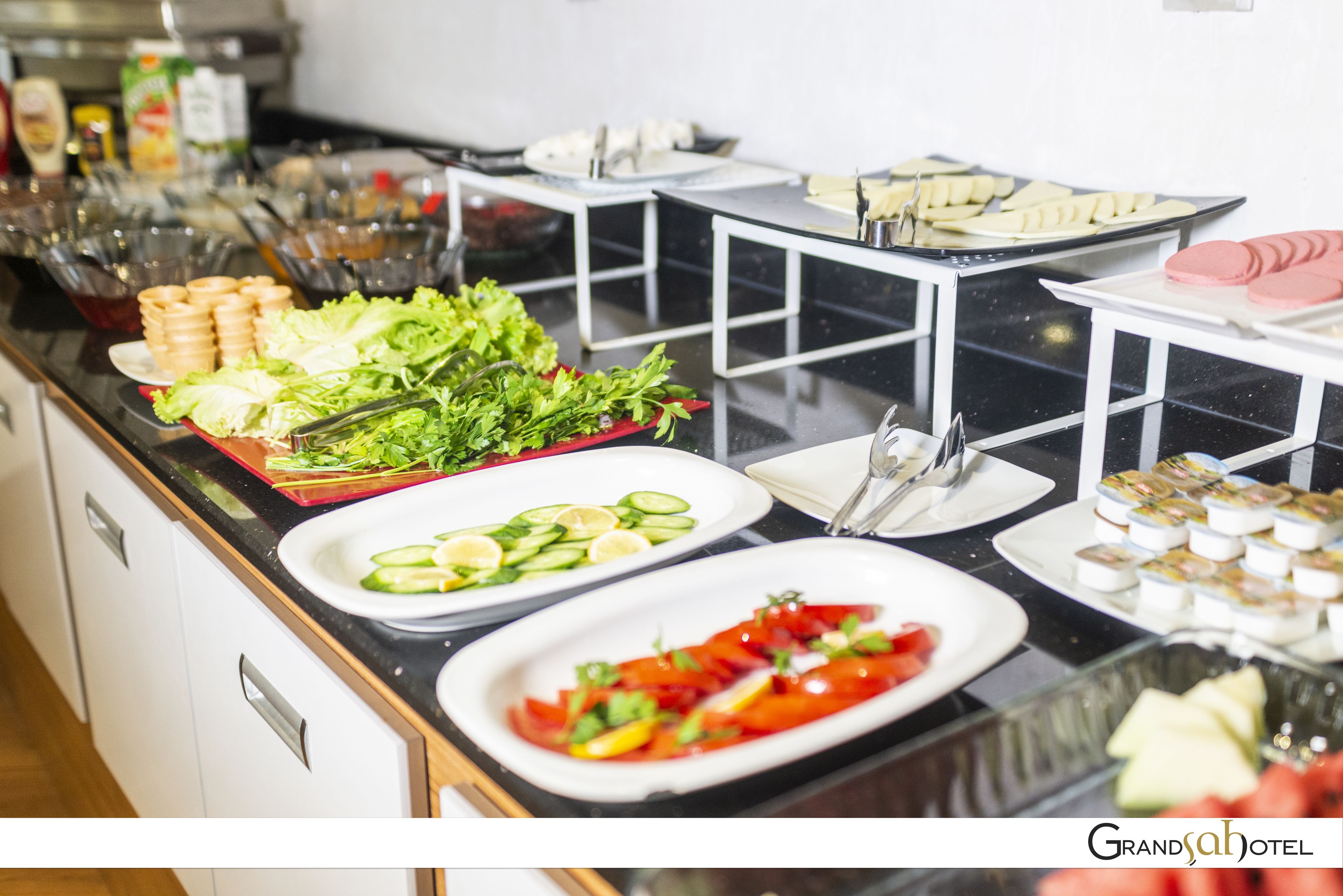 Un bufé con diversos alimentos, entre ellos ensaladas, frutas y postres.