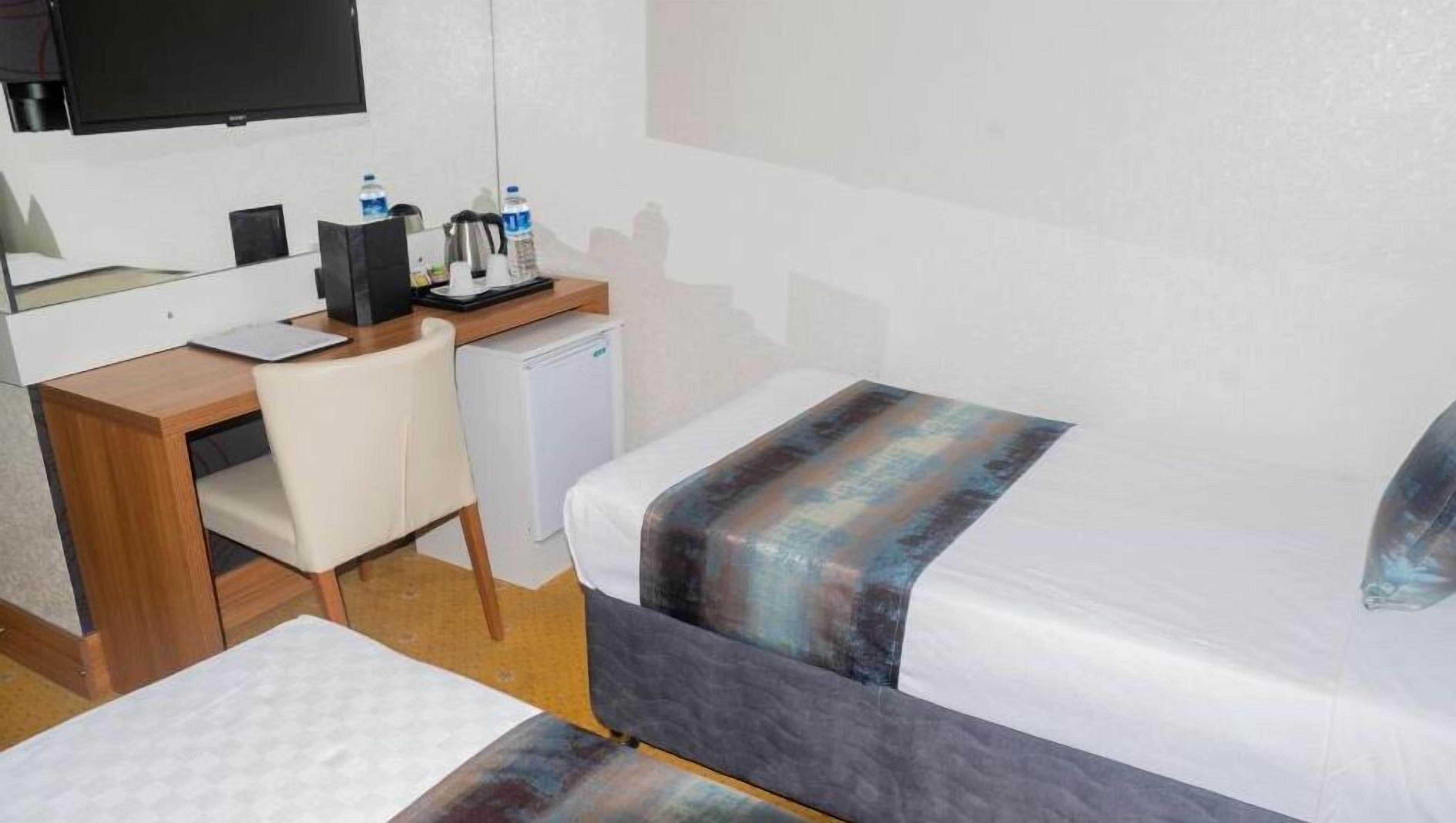 Een hotelkamer met een bed, een bureau, een stoel, een kleine koelkast en een televisie.