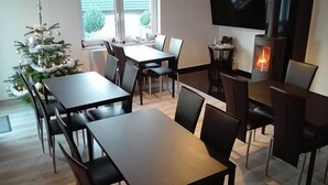 A modern dining area with a fireplace, a TV mounted on the wall, and a Christmas tree. - Guest House Vipabo (Rewal)
