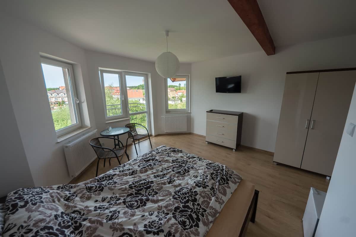 Ett sovrum med en säng, ett skrivbord, en stol, en tv och en garderob.