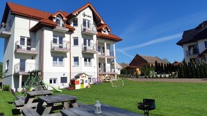 A multi-story building with balconies, a playground, and picnic tables in the yard. - Guest House Vipabo (Rewal)