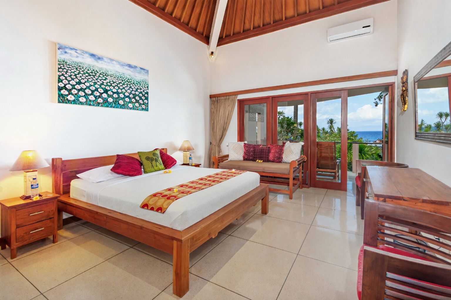 A bedroom with a bed, bedside tables, a desk, and a balcony with a view.