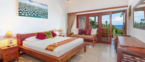 A bedroom with a bed, bedside tables, a desk, and a balcony with a view.