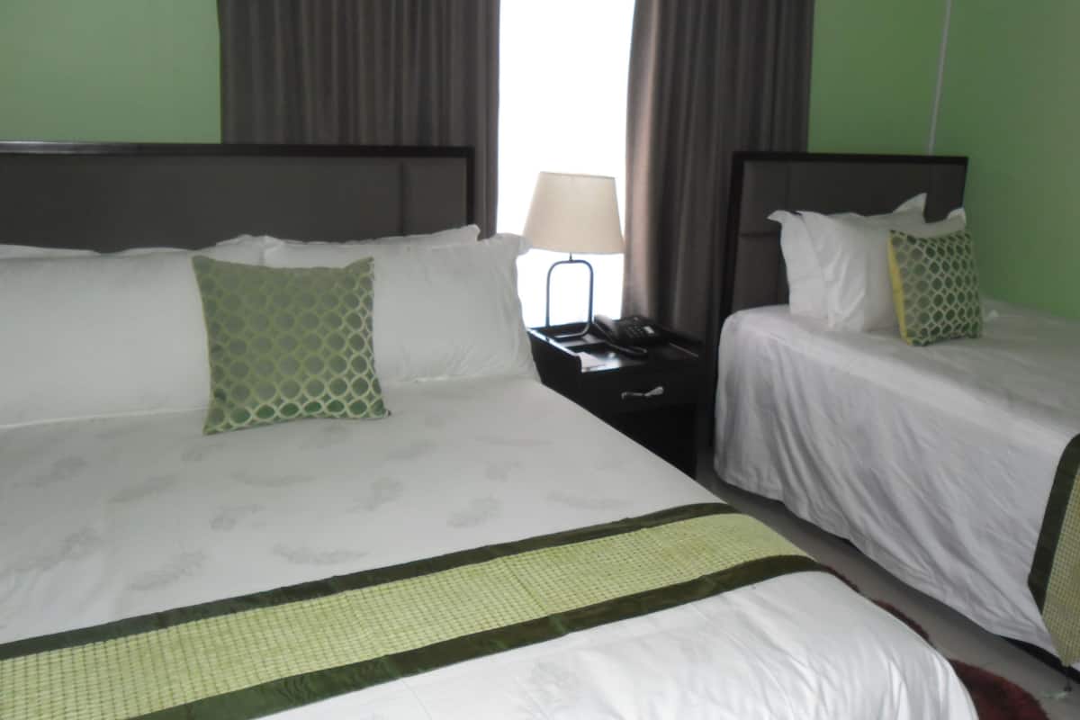 A hotel room with two beds, each with a headboard, a nightstand with a lamp, and a telephone.