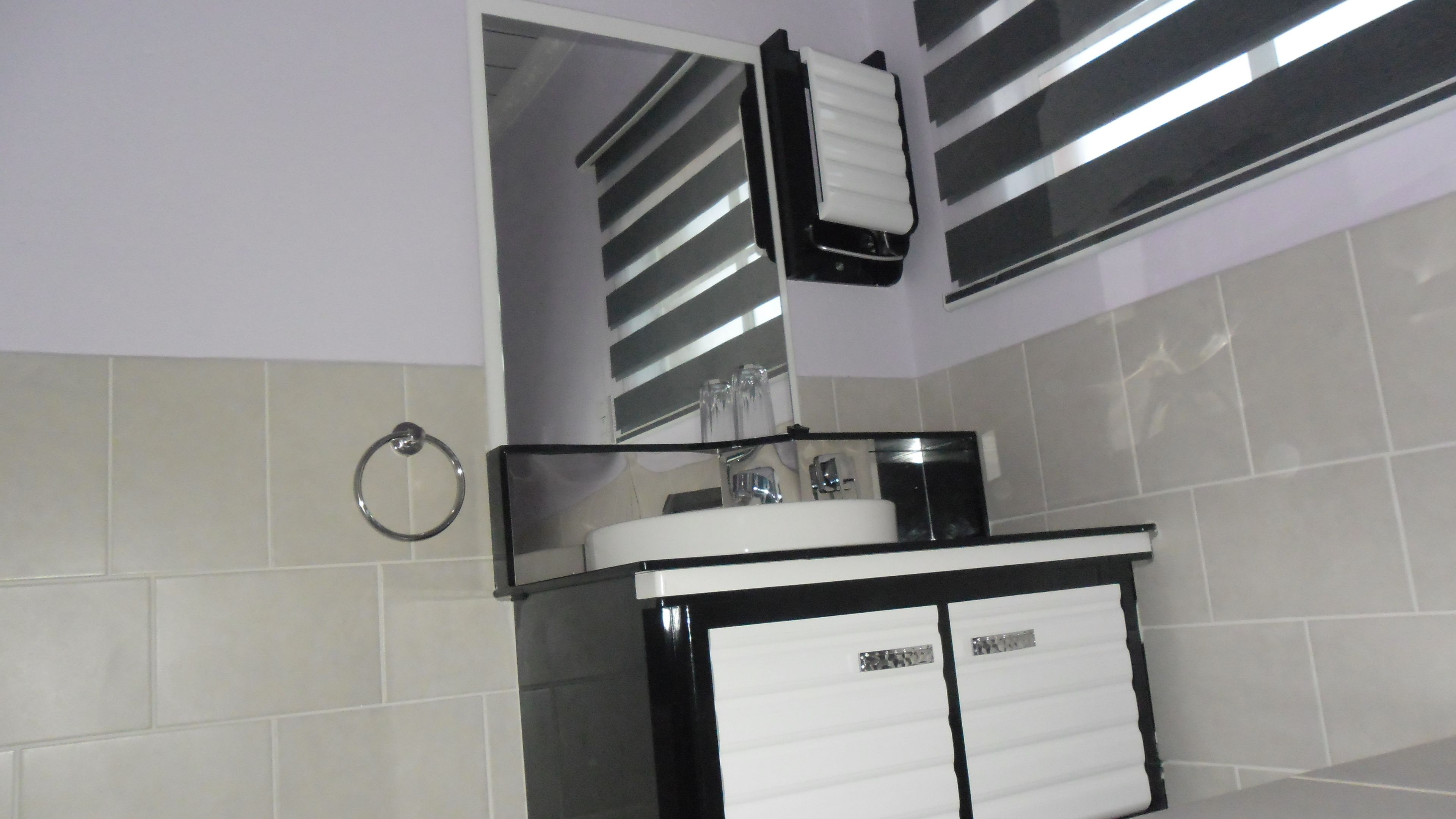 A bathroom with a white sink, a mirror, and a towel rack.