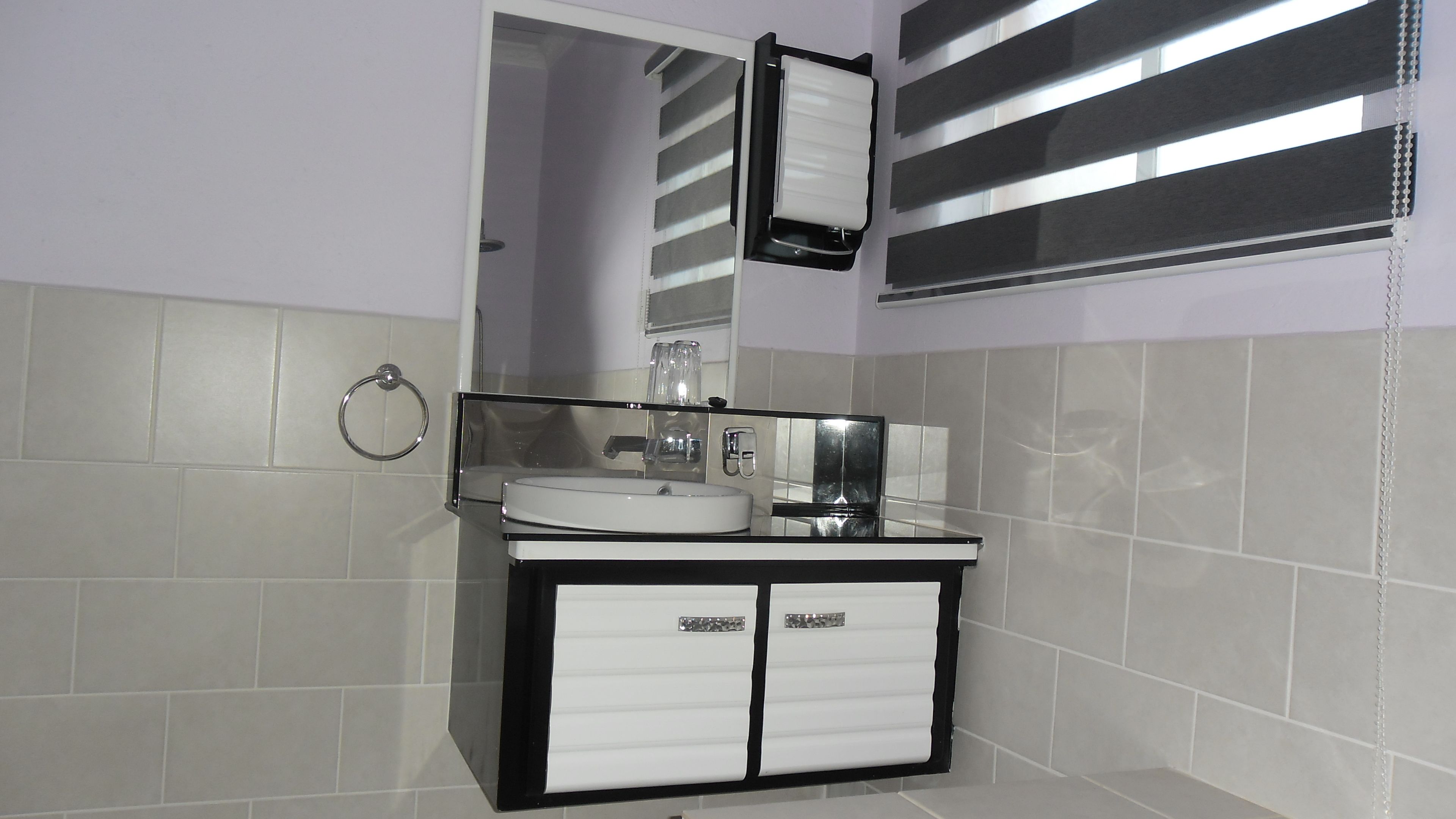 A bathroom with a white sink, a mirror, and a towel rack.