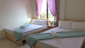 Deux lits simples avec des cadres en bois, du linge de lit blanc et des couvertures de couleur turquoise.