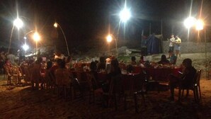 Un espace de restauration en plein air, avec des tables et des chaises, éclairé par des lampes suspendues.