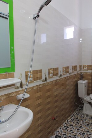 Ein Badezimmer mit Dusche, Waschbecken, Toilette und Spiegel.