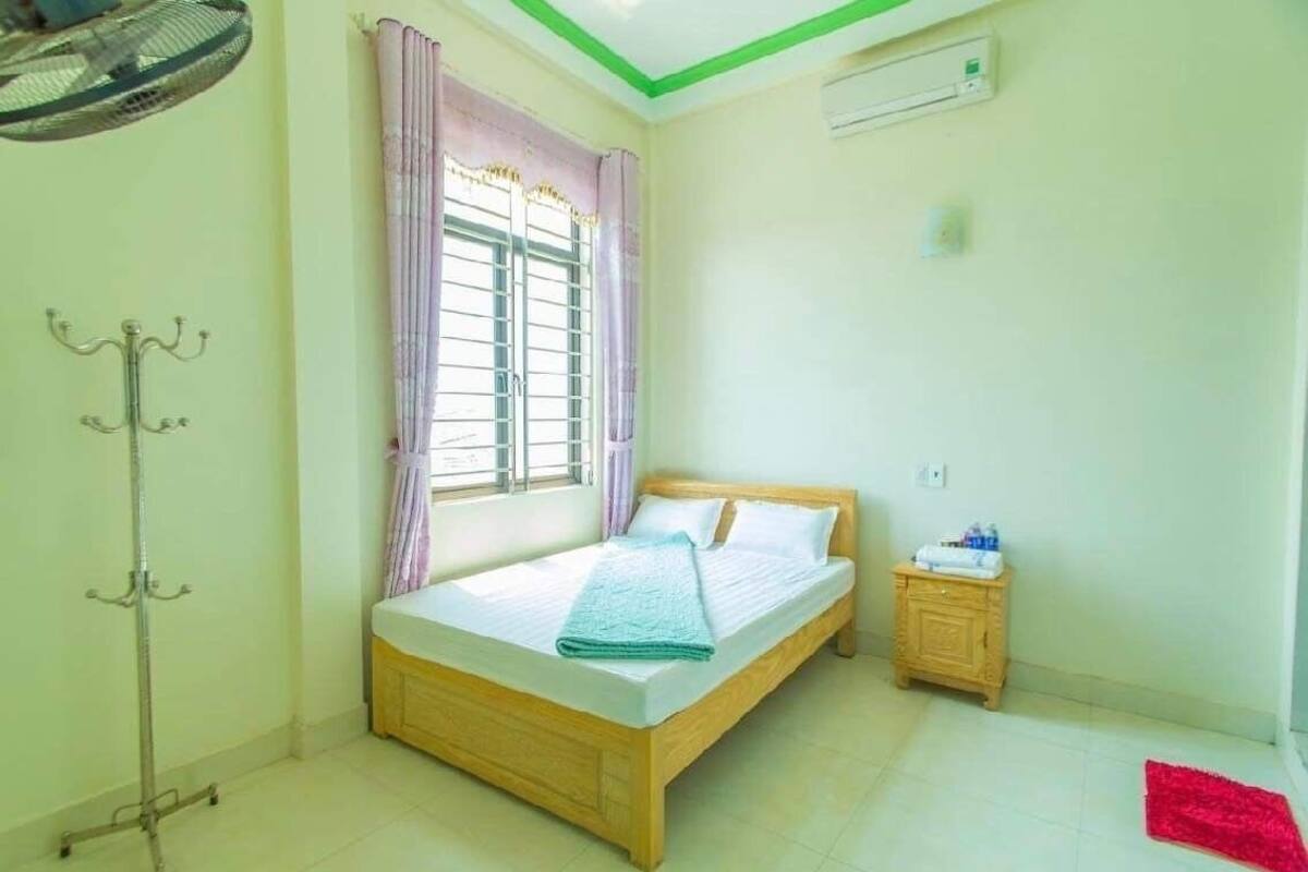 A bedroom with a bed, a nightstand, a lamp, and a window with curtains.