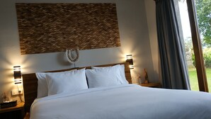 Een net opgemaakt bed met witte lakens, een houten hoofdbord en twee bedlampjes.