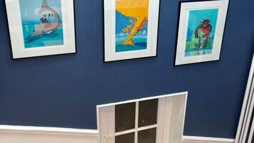 Three framed artworks on a blue wall, a window with candles and cards, and a white window frame.