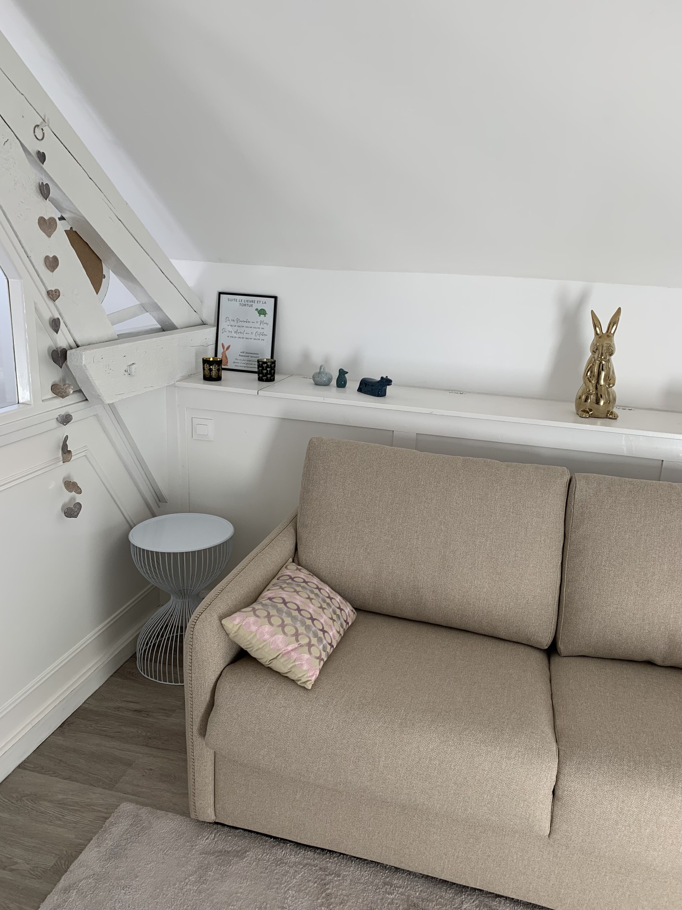 A cozy living room with a beige sofa, a small round side table, and a framed quote on the wall.