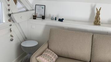 A cozy living room with a beige sofa, a small round side table, and a framed quote on the wall.