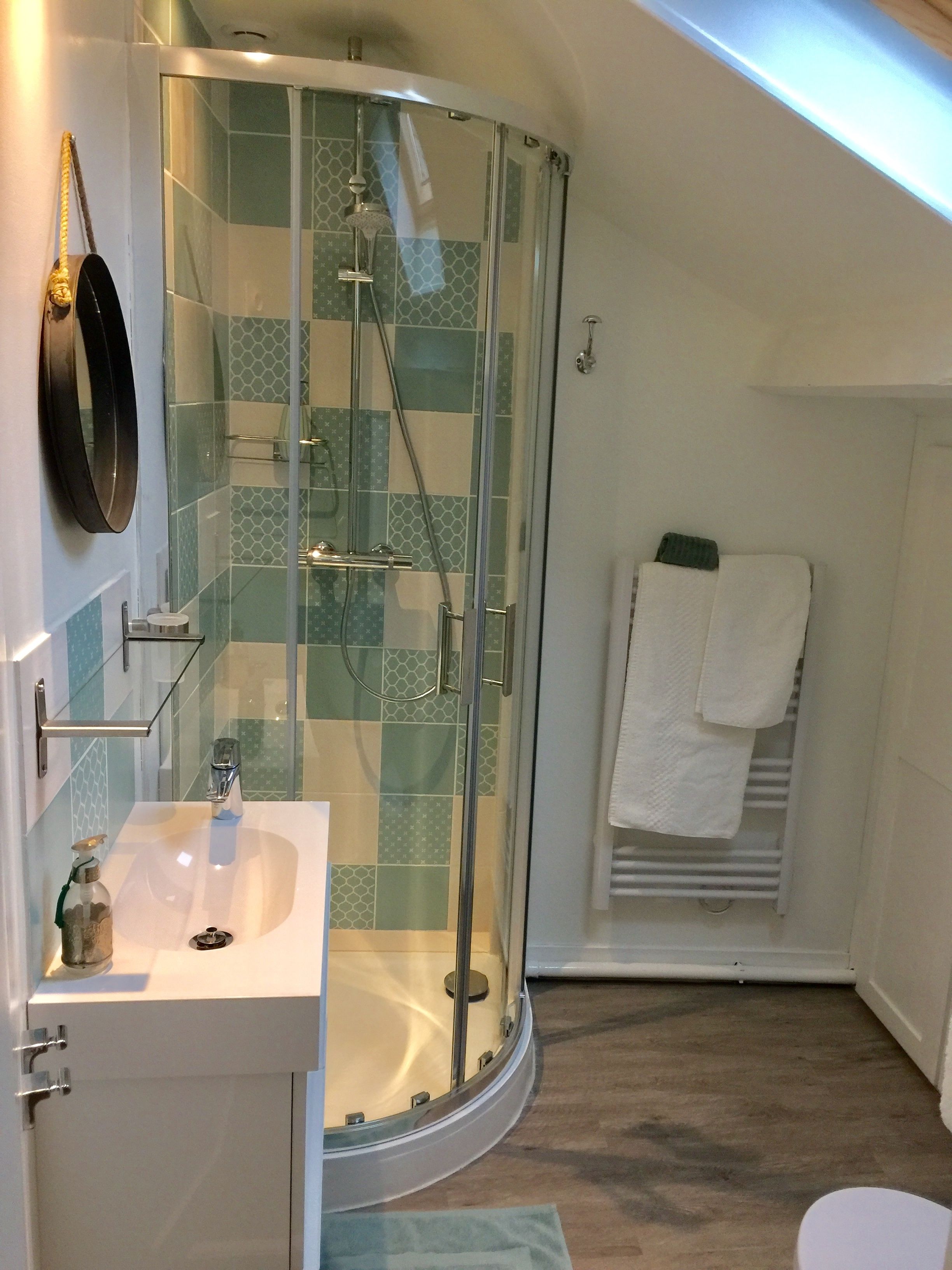 A bathroom with a glass-enclosed shower, a sink, and a towel rack.