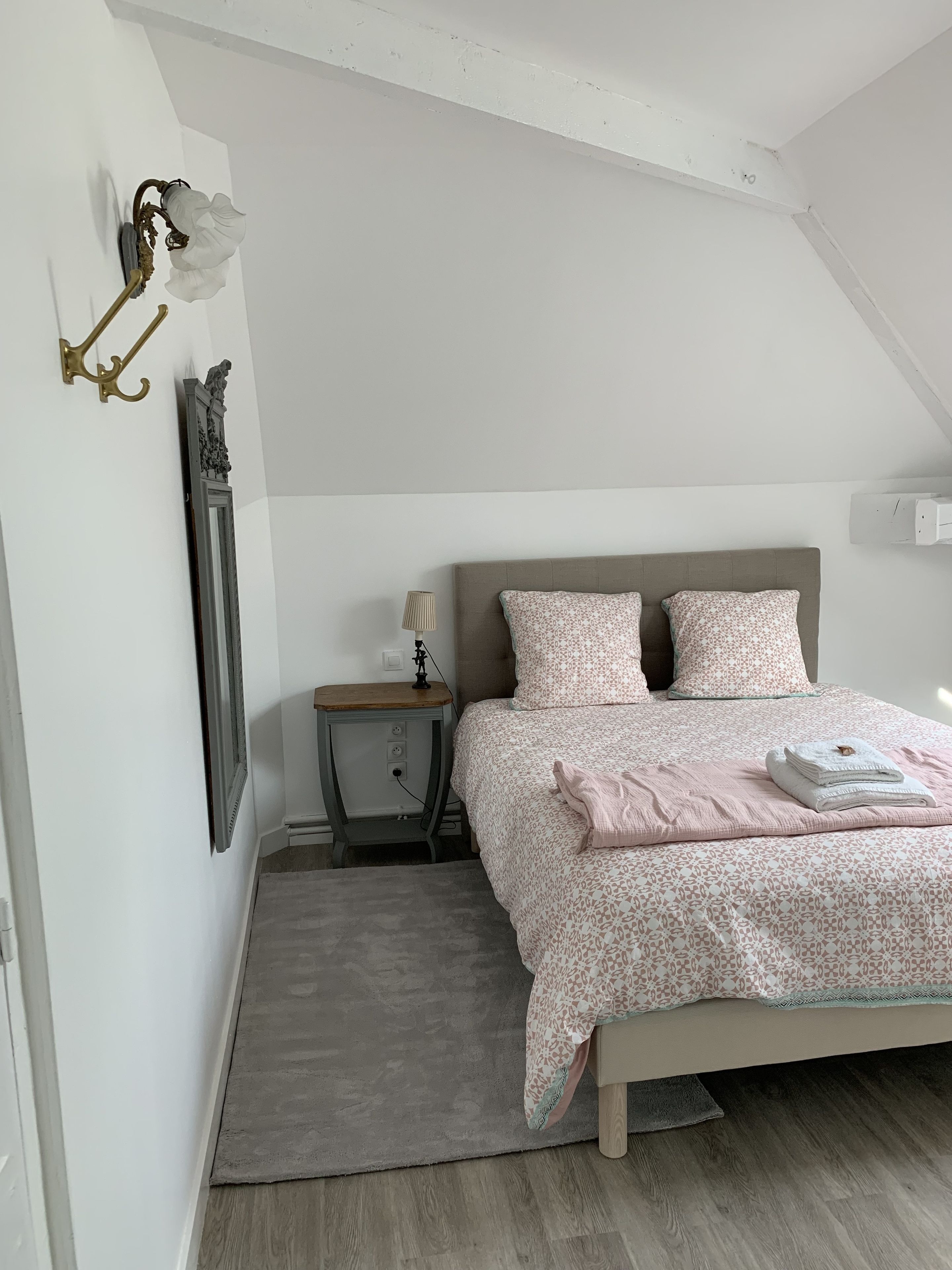 A bedroom with a bed, bedside table, lamp, and a wall-mounted light fixture.