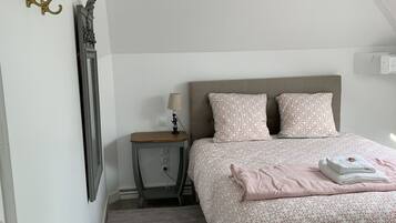 A bedroom with a bed, bedside table, lamp, and a wall-mounted light fixture.