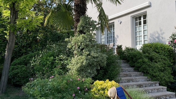 A house with a garden, a blue lounge chair, and a staircase leading to the entrance. - Maison d’hôtes Joussaume Latour (Chateau-Thierry)