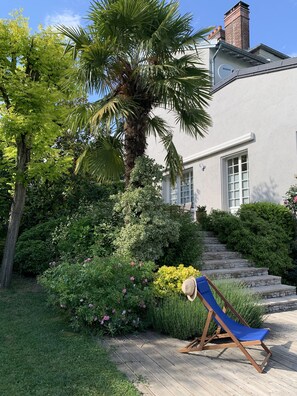 A house with a garden, a blue lounge chair, and a staircase leading to the entrance. - Maison d’hôtes Joussaume Latour (Chateau-Thierry)
