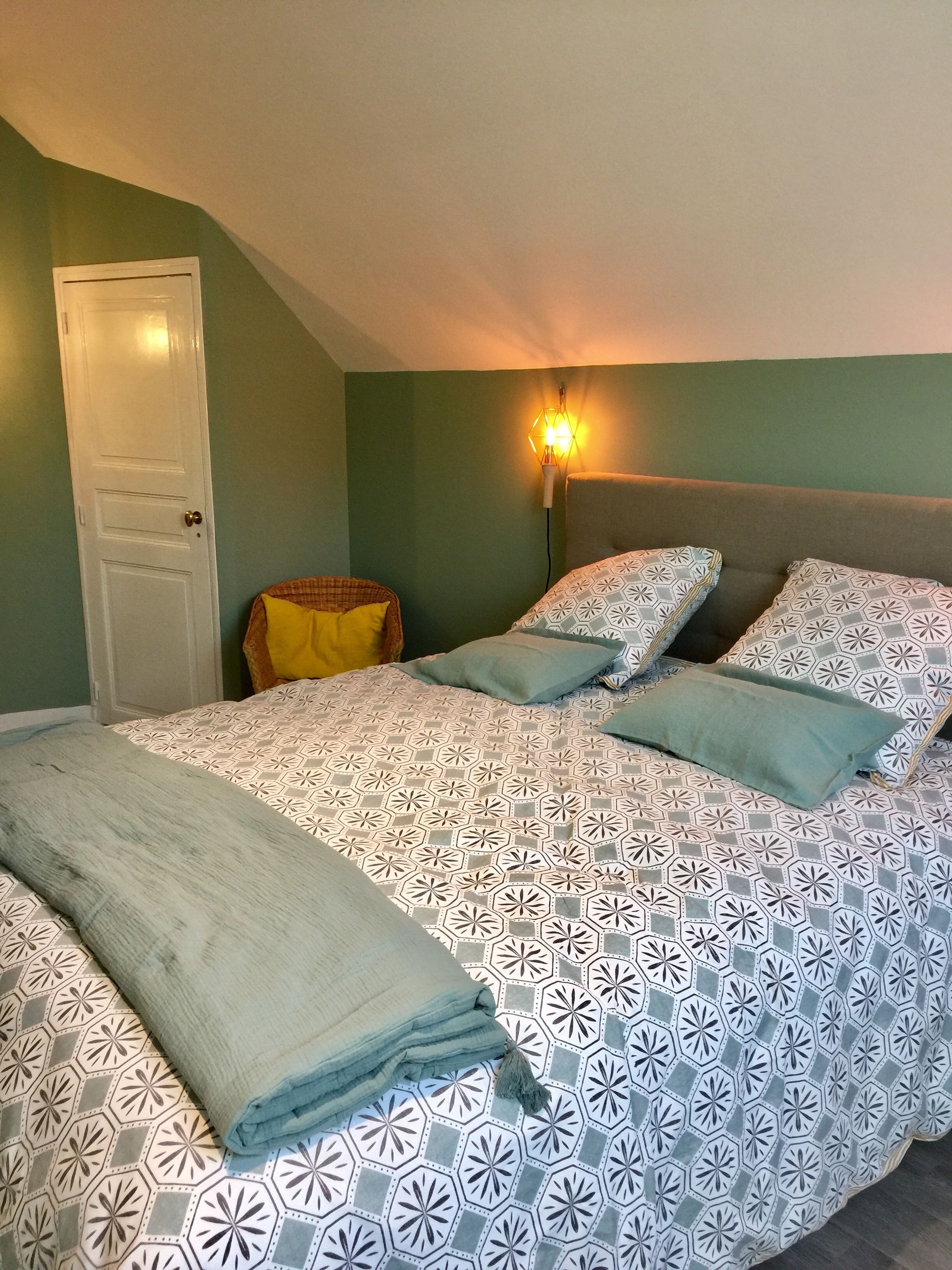 Une chambre à coucher avec un lit, une table de chevet, une lampe et une porte.