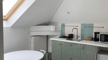 Une cuisine moderne dotée d’une lucarne, de meubles blancs et d’un petit réfrigérateur.