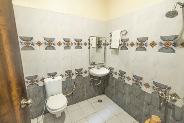Un baño con inodoro, lavamanos, ducha y paredes revestidas de azulejos.