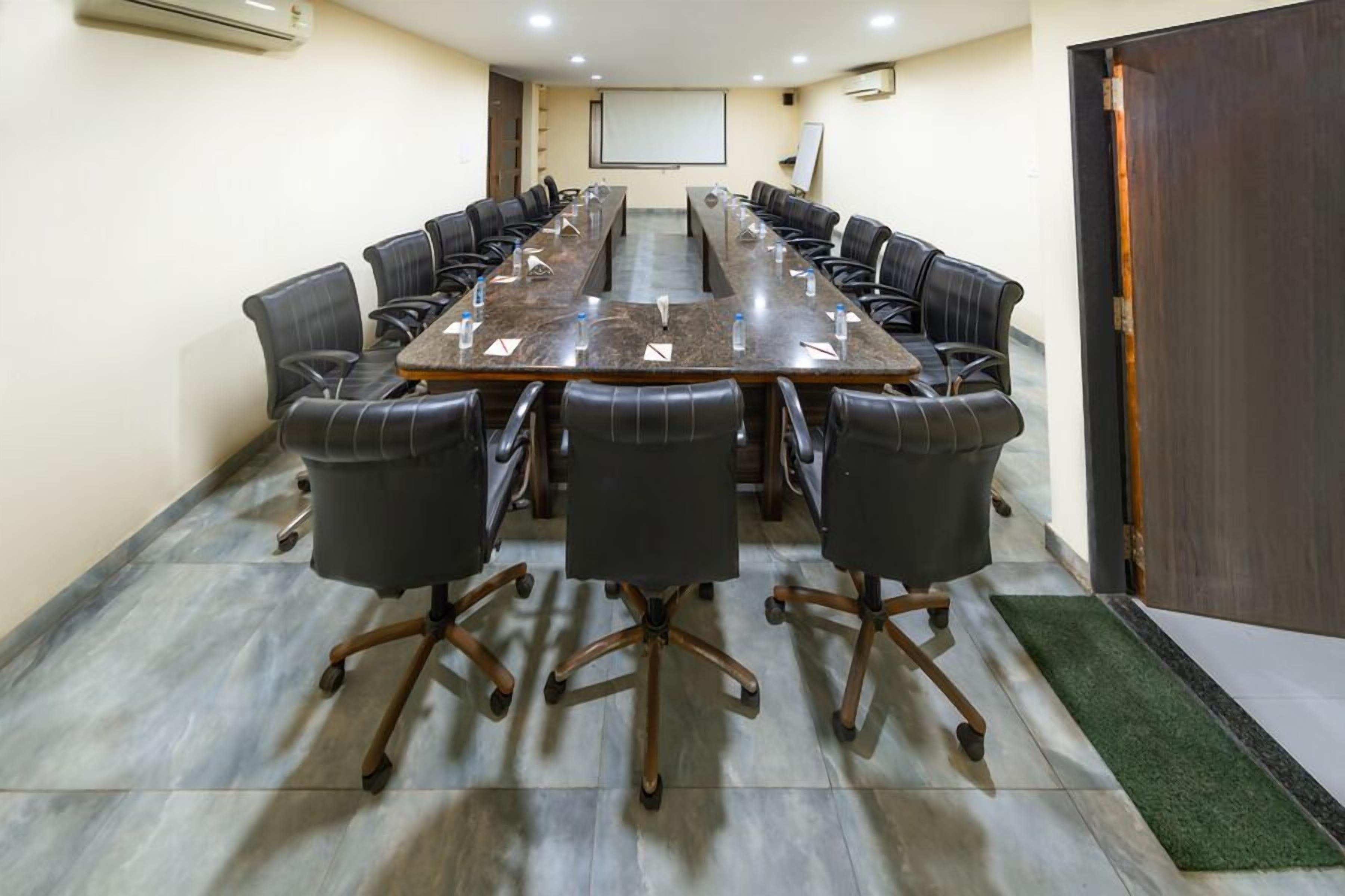 A conference room with a long table and chairs, a projector screen, and a whiteboard.
