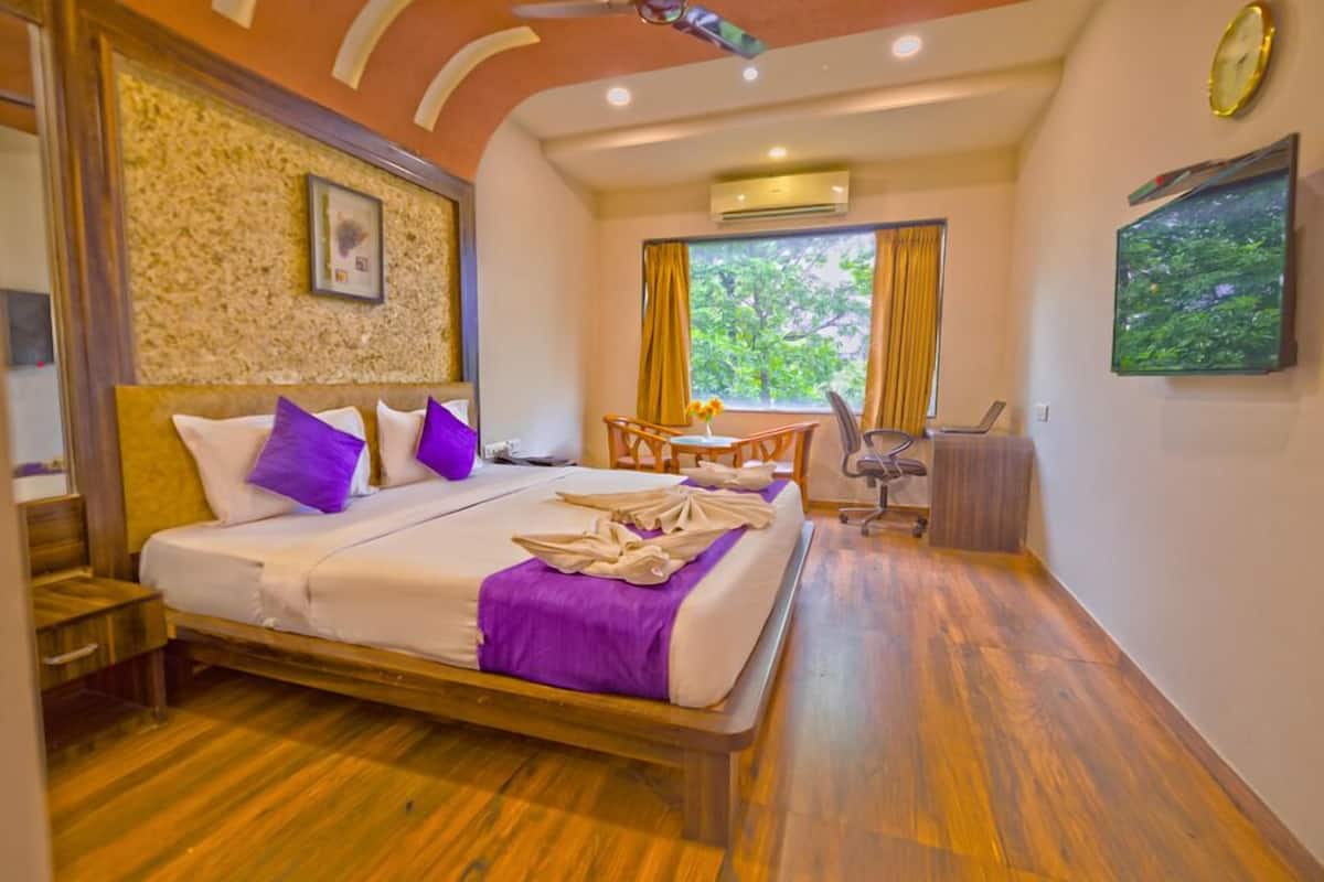 Quarto de hotel com cama, escrivaninha e uma cadeira.
