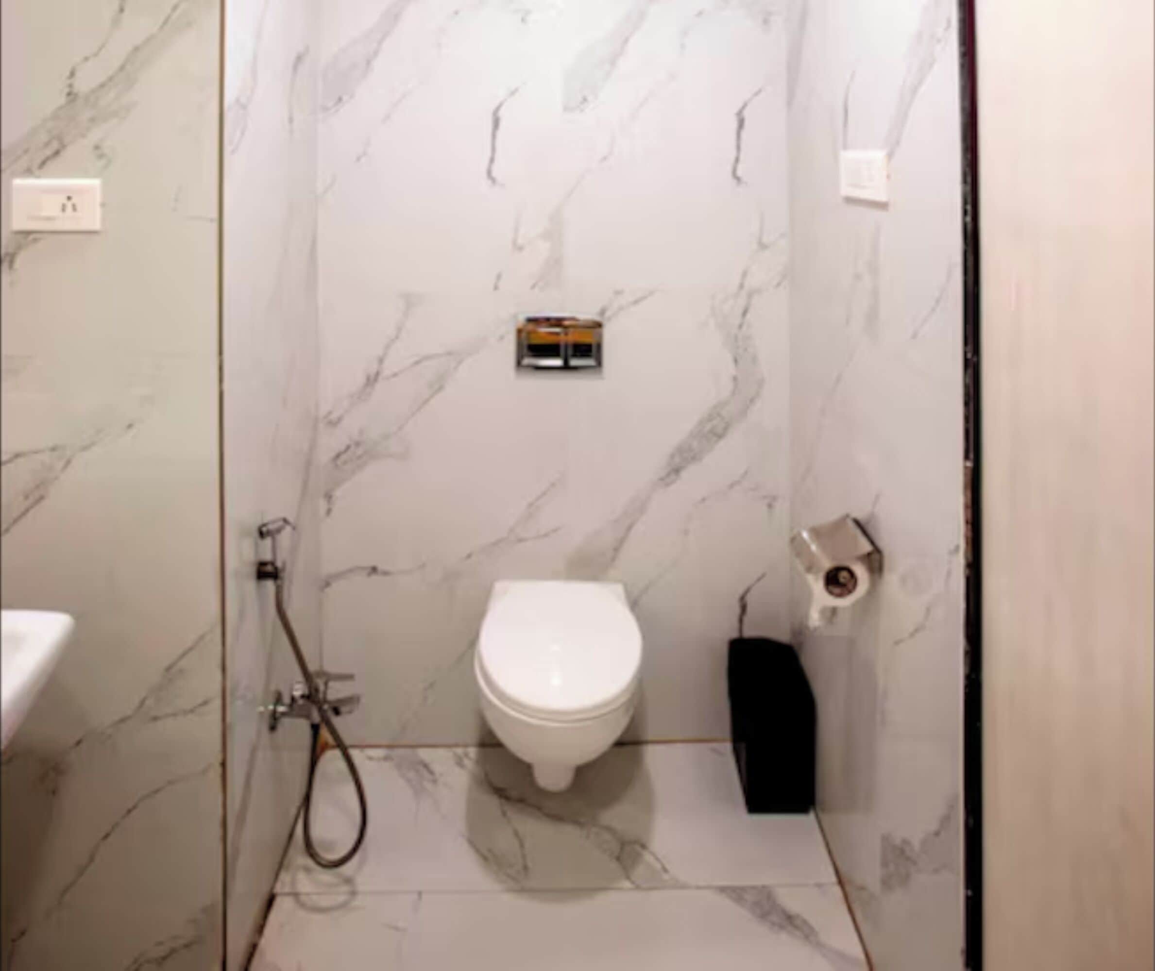 A bathroom with a toilet, a shower, and a marble wall.