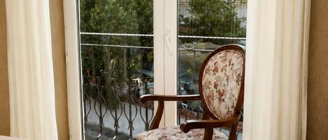 Un balcón con una silla y vistas a un edificio y árboles.