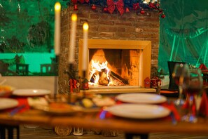 A fireplace with a fire, surrounded by Christmas decorations and a dining table set with plates and candles. - Pelit Boutique Hotel (Adalar)