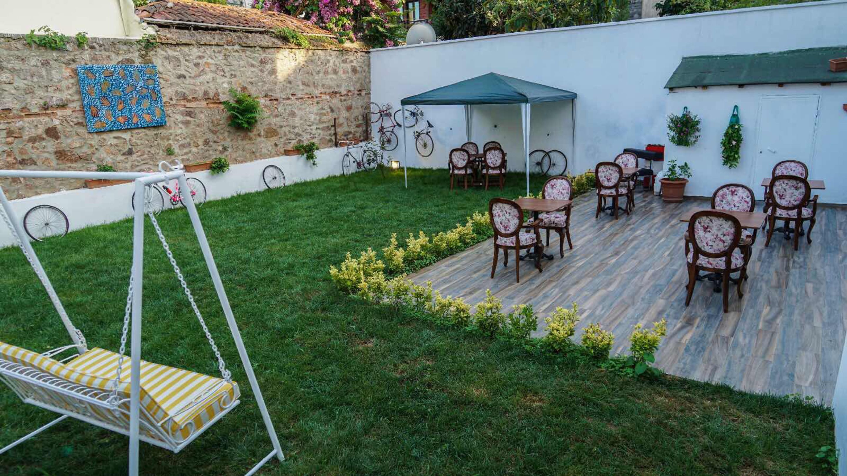 Un patio con mobiliario exterior, un columpio y un muro de piedra con plantas.