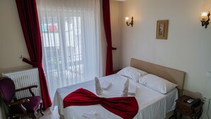 A hotel room with a bed, a chair, a nightstand, and a window with curtains. - Pelit Boutique Hotel (Adalar)
