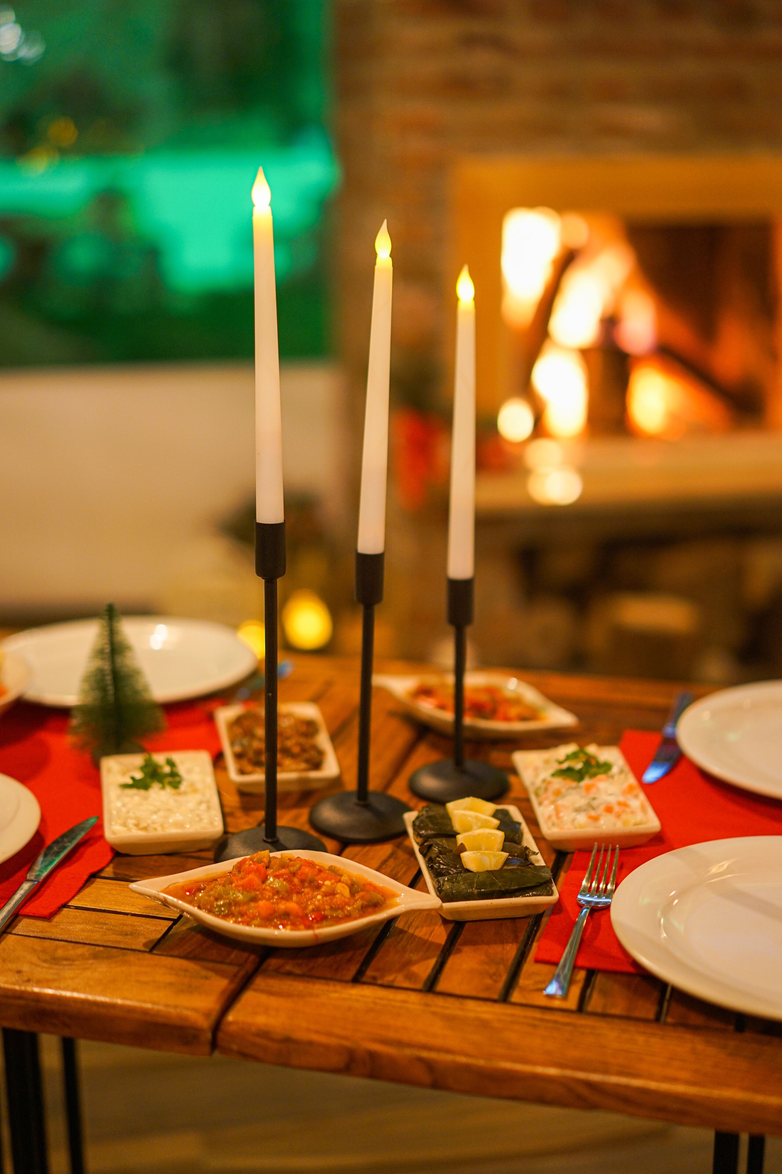 A dining table with candles, plates, and food.