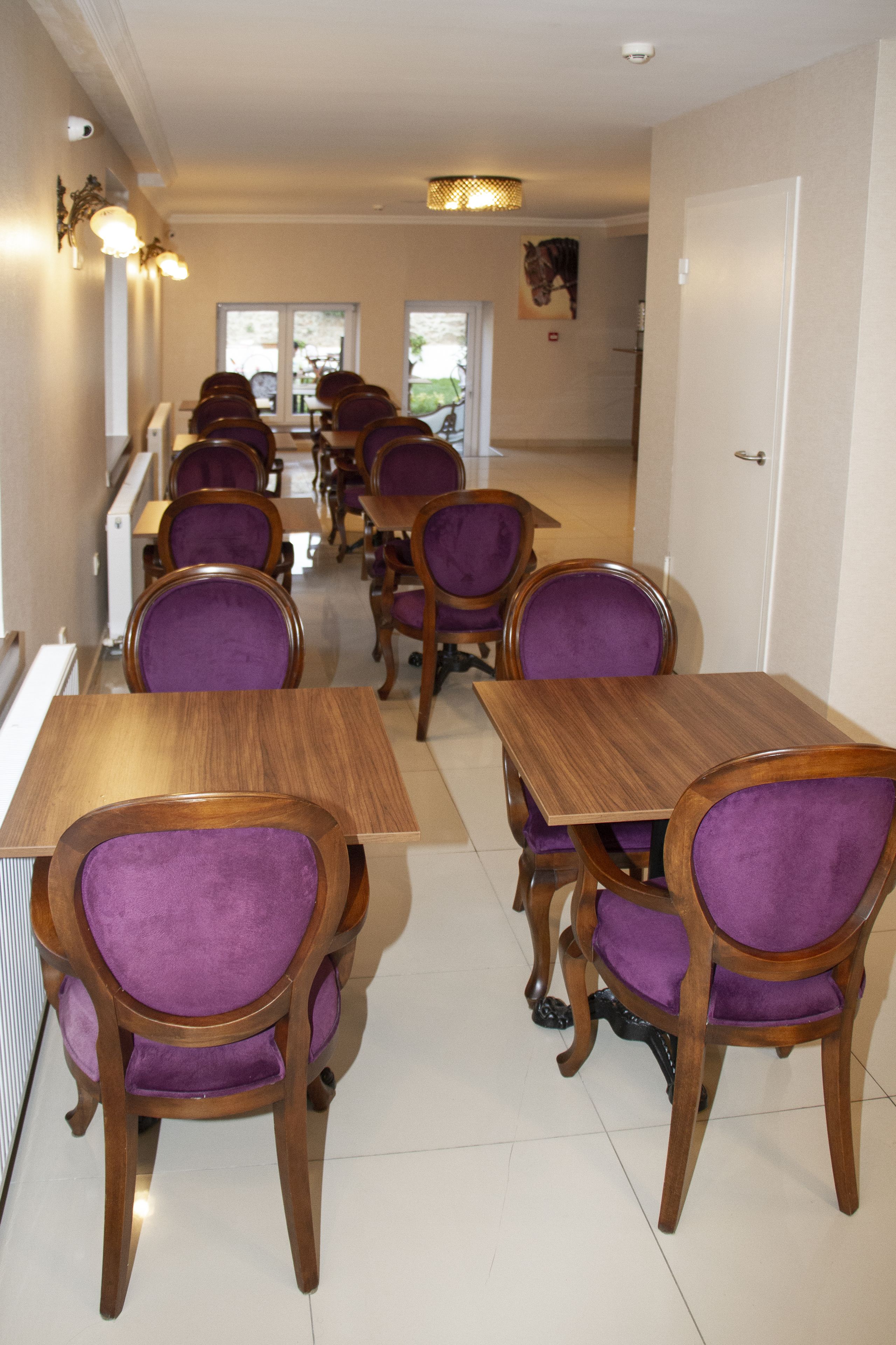 A dining area with wooden tables and purple upholstered chairs, arranged in rows.