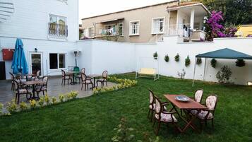 Um pátio com mobiliário externo, um pequeno jardim e um edifício branco com varandas.