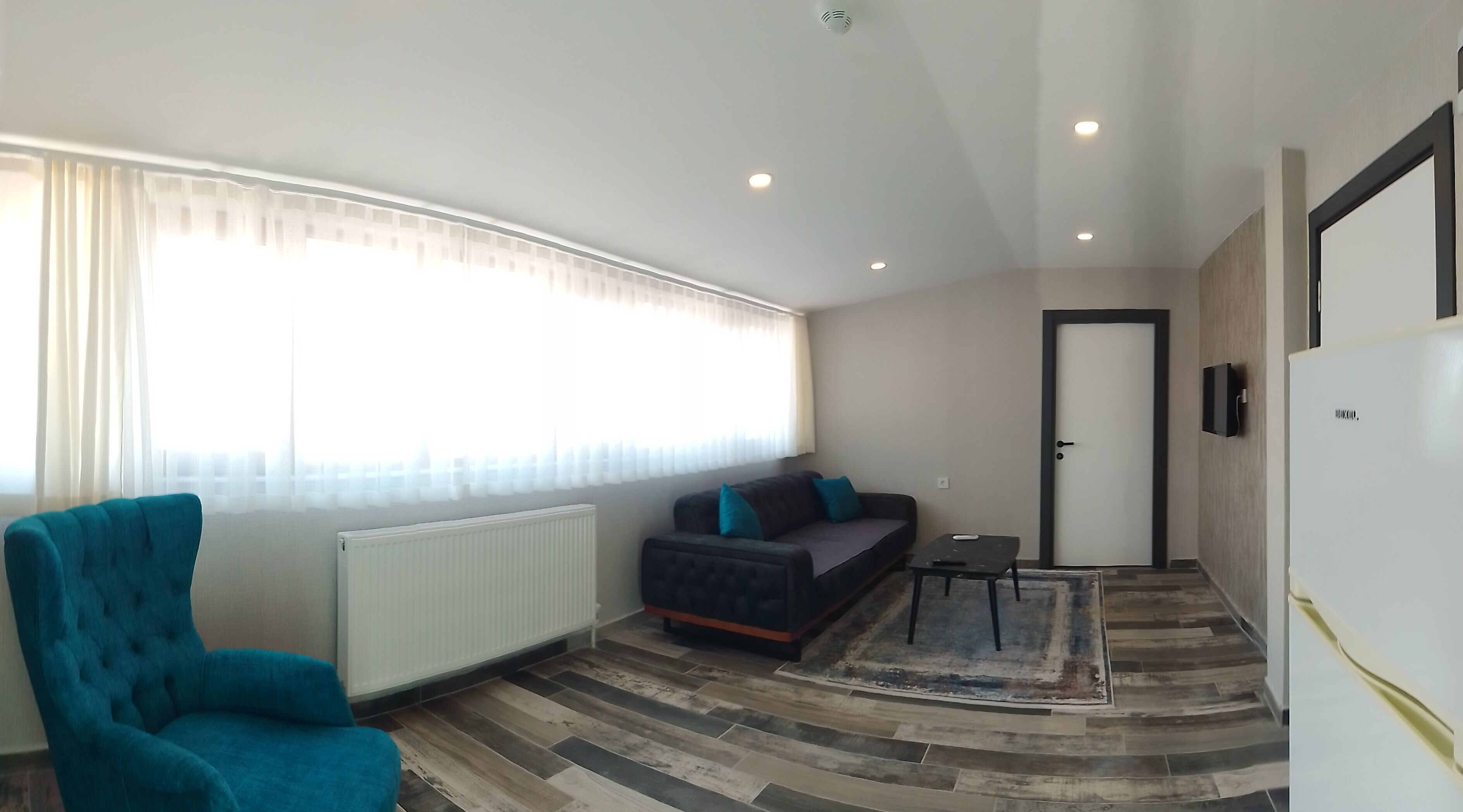 Una sala de estar moderna con un sofá, una silla, una mesita y una puerta.