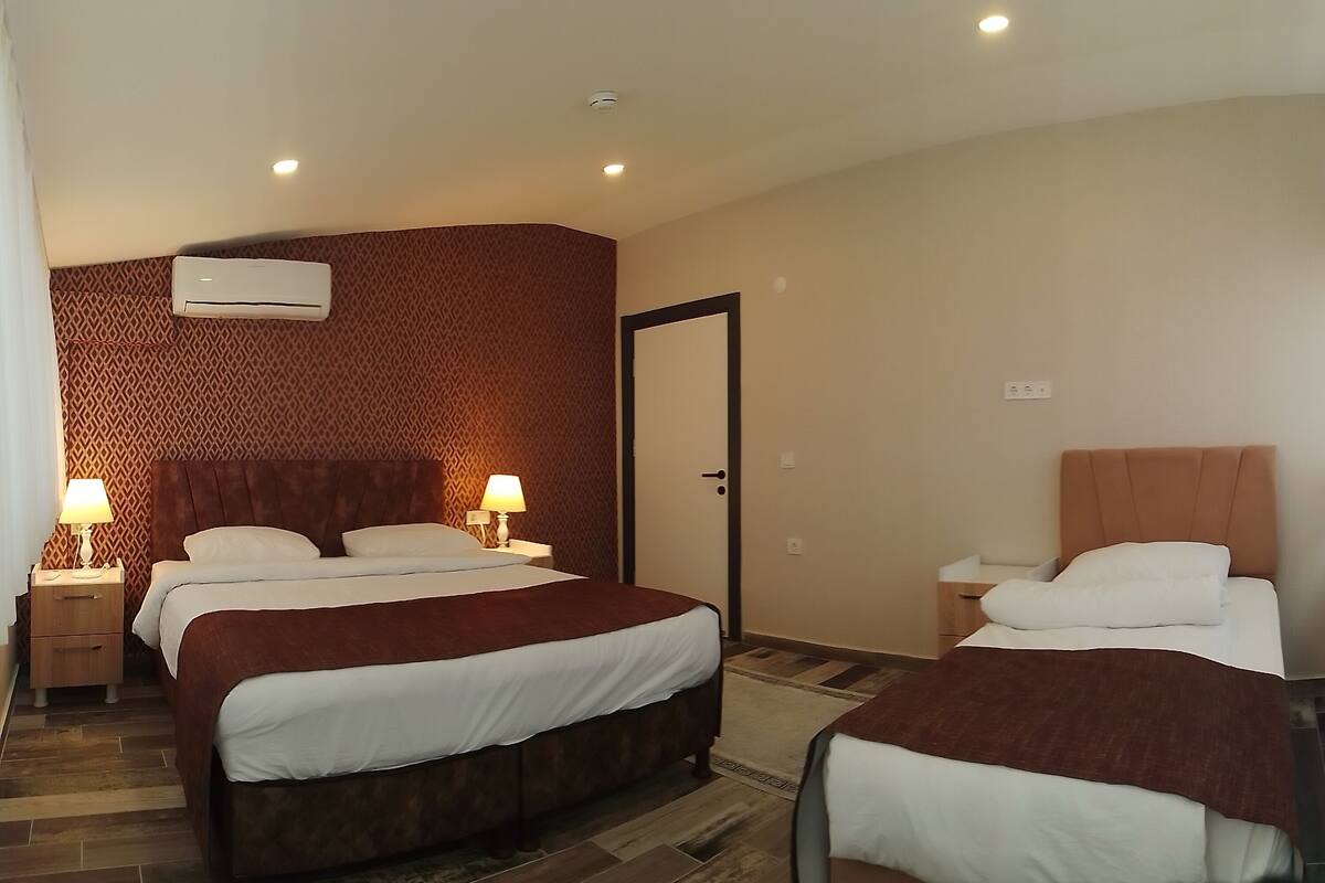 A hotel room with two beds, a patterned wall, a door, and a window with curtains.