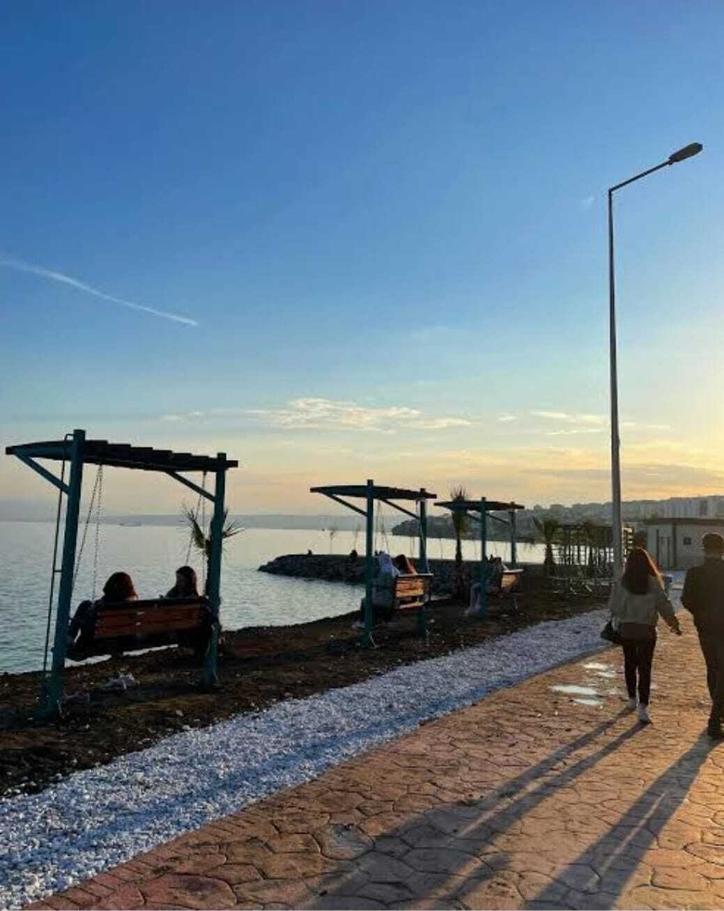 Une promenade en bord de mer, agrémentée de bancs et d’un chemin piétonnier pavé.
