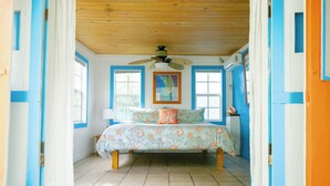 A bedroom with a bed, a ceiling fan, and a window. - Andros Beach Club (Rolle Town)